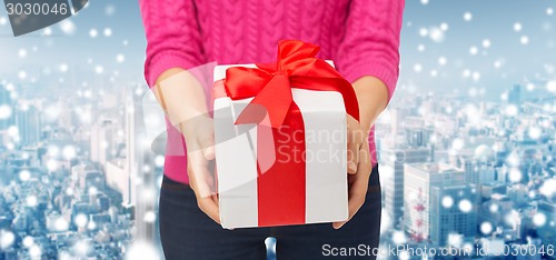 Image of close up of woman in pink sweater holding gift box