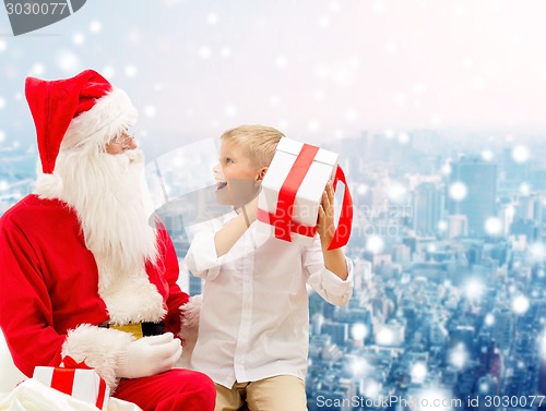 Image of smiling little boy with santa claus and gifts
