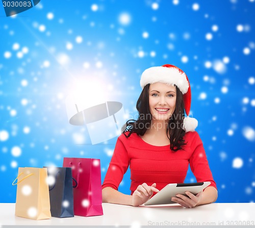 Image of smiling woman with shopping bags and tablet pc