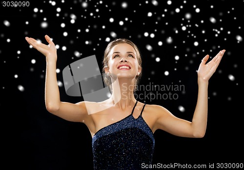 Image of smiling woman raising hands and looking up