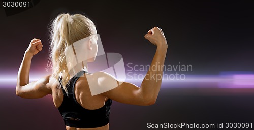 Image of sporty woman from the back flexing her biceps