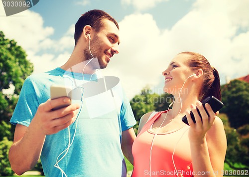 Image of two smiling people with smartphones outdoors
