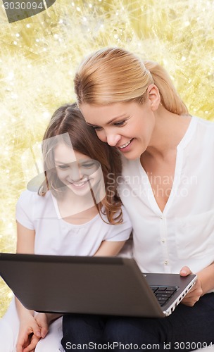 Image of smiling mother and little girl with laptop