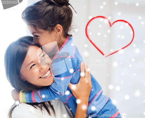 Image of smiling little girl and mother hugging indoors