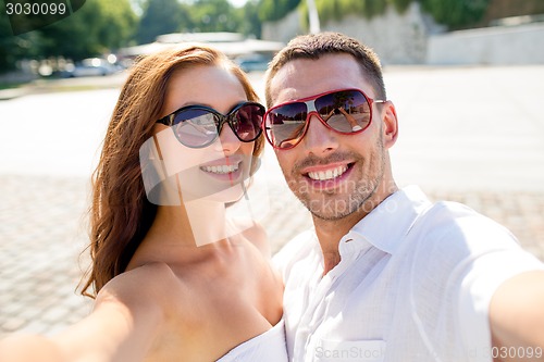 Image of smiling couple wearing sunglasses making selfie