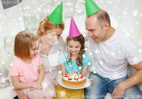 Image of happy family with two kids in party hats at home