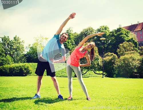 Image of smiling couple stretching outdoors