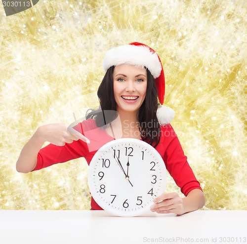 Image of smiling woman in santa helper hat with clock