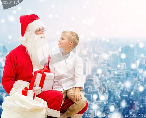 Image of smiling little boy with santa claus and gifts
