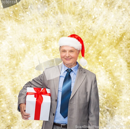 Image of smiling man in suit and santa helper hat with gift