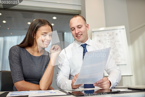 Image of smiling businesspeople with papers in office