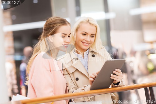 Image of happy young women with tablet pc and shopping bags