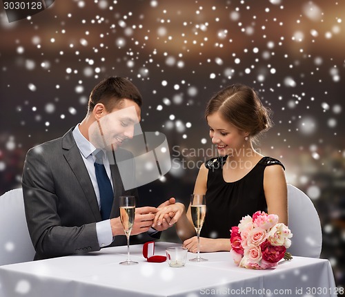 Image of smiling couple with red gift box at restaurant