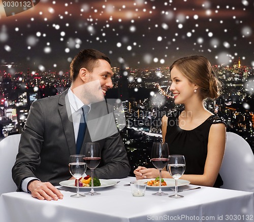 Image of smiling couple eating main course at restaurant