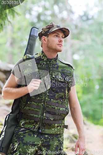 Image of young soldier or hunter with gun in forest