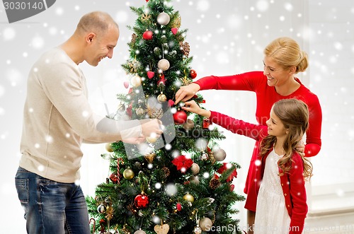 Image of smiling family decorating christmas tree at home
