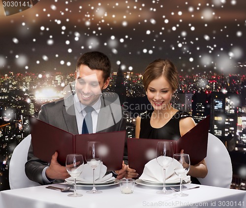 Image of smiling couple with menus at restaurant