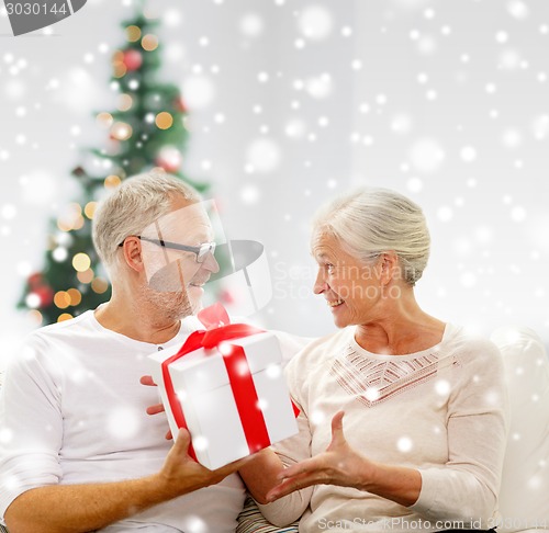 Image of happy senior couple with gift box at home