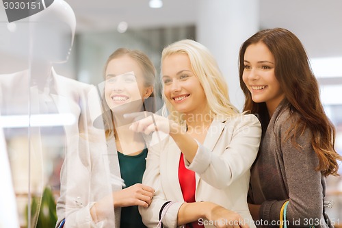 Image of happy young women with shopping bags in mall