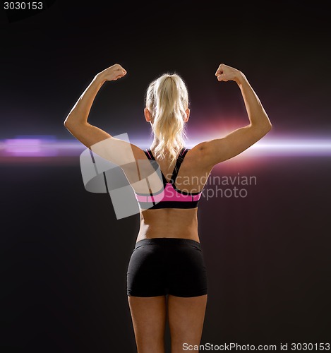 Image of sporty woman from the back flexing her biceps