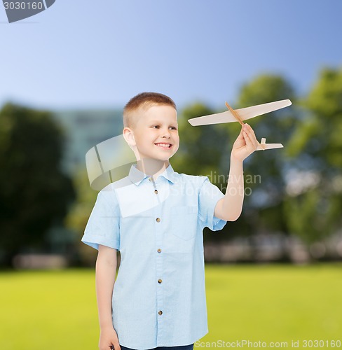 Image of smiling little boy holding a wooden airplane model