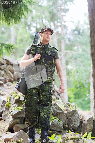 Image of young soldier or hunter with gun in forest