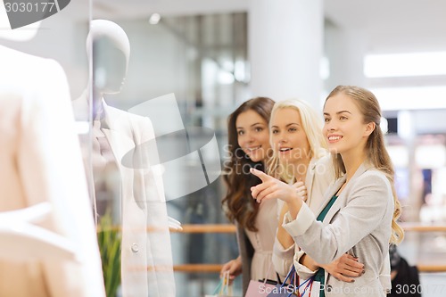 Image of happy young women with shopping bags in mall