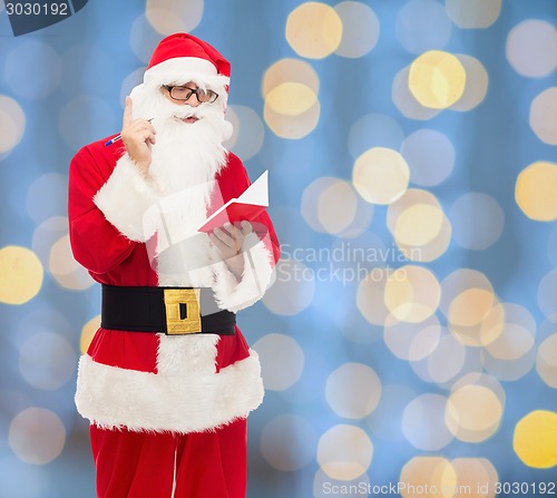 Image of man in costume of santa claus with notepad