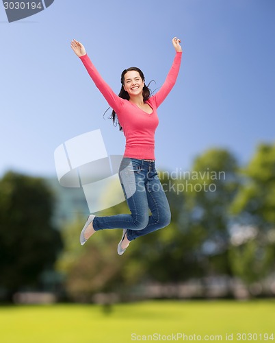 Image of smiling young woman jumping in air