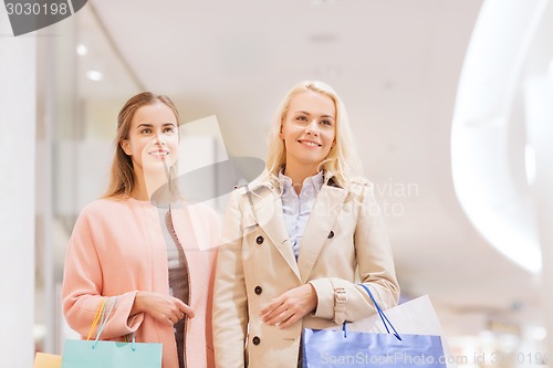 Image of happy young women with shopping bags in mall