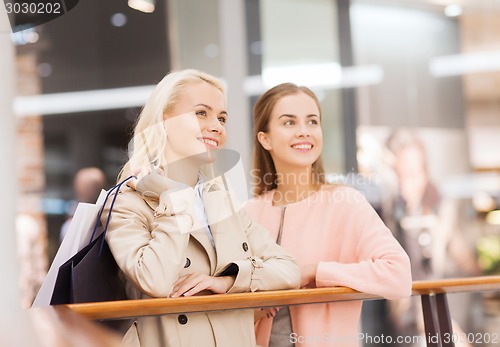 Image of happy young women with shopping bags in mall