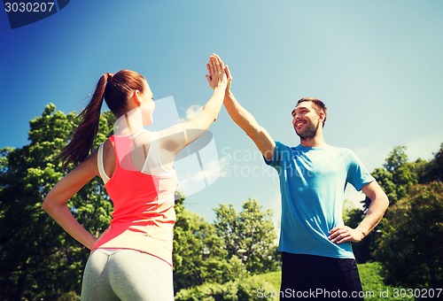 Image of two smiling people making high five outdoors