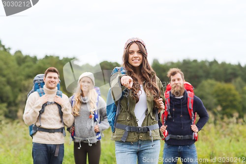 Image of smiling hikers with backpacks pointing finger