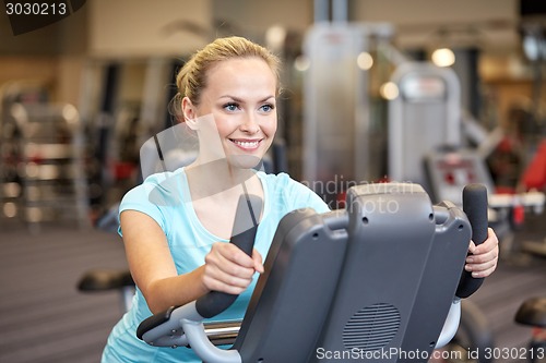 Image of smiling woman exercising on exercise bike in gym
