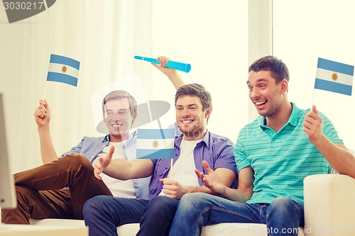 Image of happy male friends with flags and vuvuzela