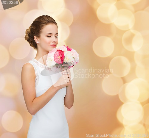 Image of smiling woman in white dress with bouquet of roses