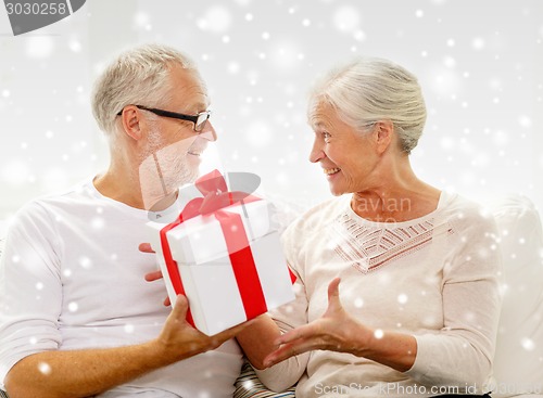 Image of happy senior couple with gift box at home