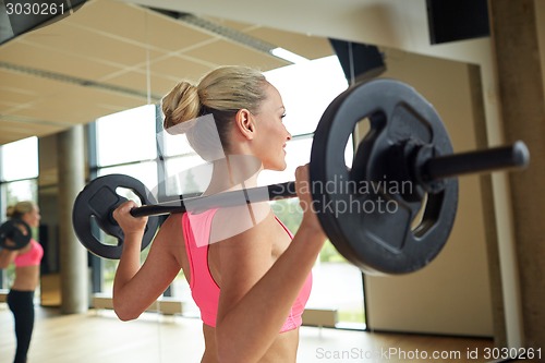 Image of sporty woman exercising with barbell in gym