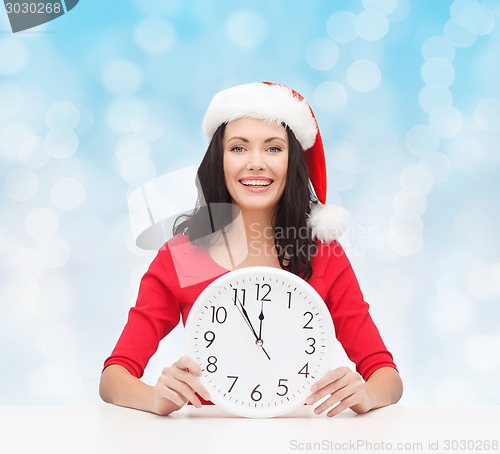 Image of smiling woman in santa helper hat with clock