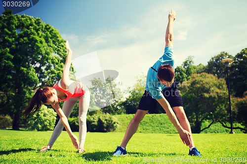 Image of smiling couple stretching outdoors