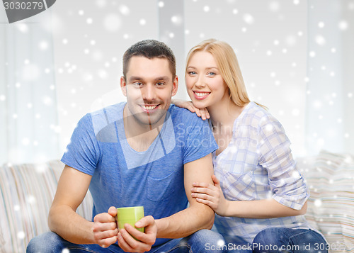 Image of smiling couple with cup of tea or coffee at home