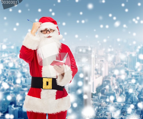 Image of man in costume of santa claus with notepad