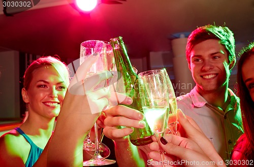 Image of smiling friends with wine glasses and beer in club