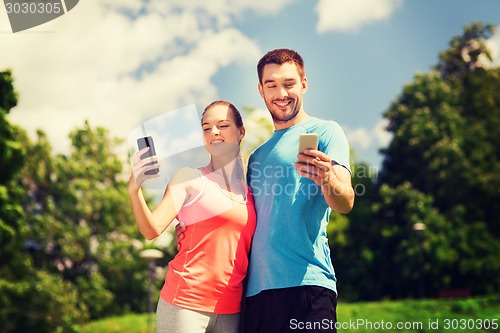 Image of two smiling people with smartphones outdoors