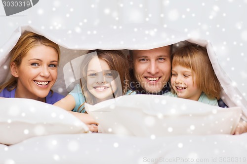 Image of happy family with two kids under blanket at home