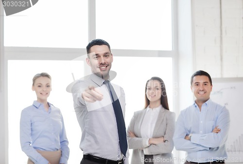 Image of businessman in office pointing finger at you