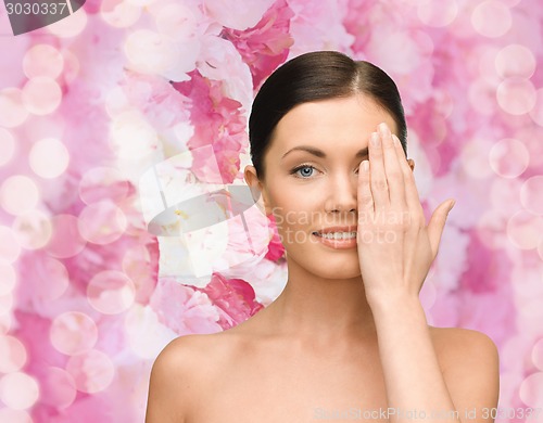 Image of smiling young woman covering face with hand