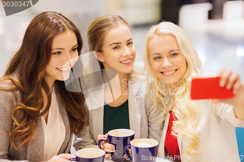 Image of smiling young women with cups and smartphone