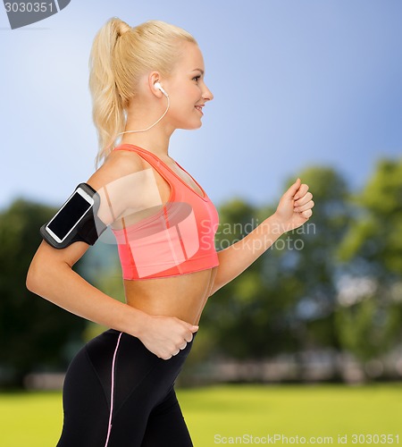 Image of sporty woman running with smartphone and earphones