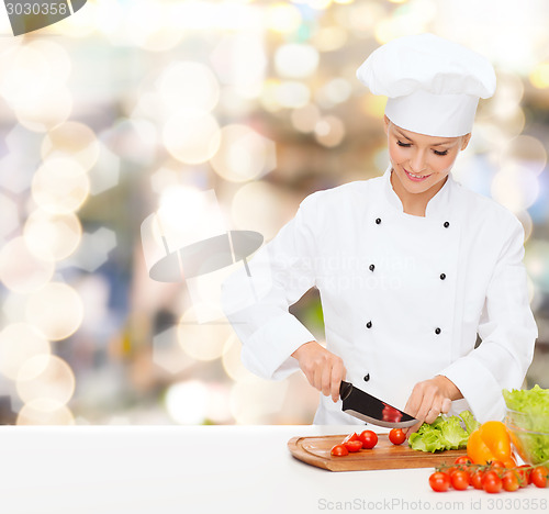 Image of smiling female chef chopping vegetables